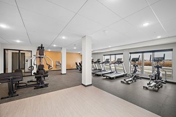 A gym with a variety of equipment including treadmills, stationary bikes, and weight machines at The Landing at Amber Fields Apartments, Rosemount, MN, 55068